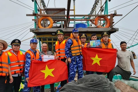 Vietnam Coast Guard officers present the national flag to fishermen at sea. (Photo: VNA)