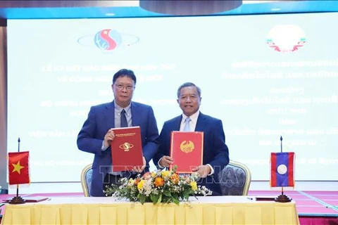 President of the Vietnam Academy of Science and Technology (VAST) Chau Van Minh (L) and Lao Minister of Technology and Communications Boviengkham Vongdara exchanges the minutes of cooperation. (Photo: VNA)