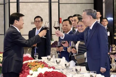越南国家主席苏林与老挝人民革命党中央总书记、国主席通伦举杯庆祝越老关系的良好发展。图自越通社