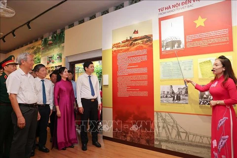 People are told about photo displayed at the exhibition. (Photo: VNA)