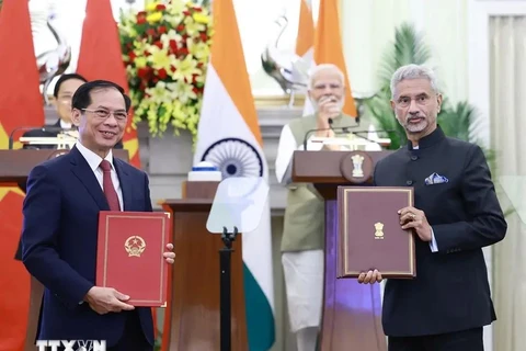 Leaders of the foreign ministries of Vietnam and India exchange an agreement between their governments allowing family members of diplomatic and consular staff to work for income. (Photo: VNA)