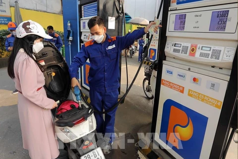 A customer buys petrol at a petrol station in Hanoi. The retail prices of E5RON92 bio-fuel and all petrol products decrease from 3pm on July 11 (Photo: VNA)