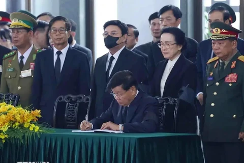 El secretario general del Partido Popular Revolucionario y presidente de Laos, Thongloun Sisoulith, escribe en el libro de condolencias. (Fuente: VNA)