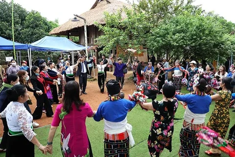 Des touristes et des personnes issues de l'ethnie Thái au Village culturel et touristique des ethnies du Vietnam. Photo d'archives: baotintuc