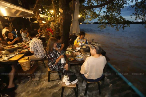 Customers of a riverside 'moo krata' (barbecued pork buffet) in Nonthaburi's Soi Phibulsongkhram 21 do not mind having their feet soaked during high tide in the Chao Phraya River on Sunday. Some describe it as a unique dining experience. (Photo:bangkokpost.com) 