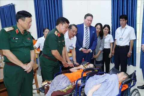 Le vice-ministre de la Défense, Hoàng Xuân Chiên, et l’ambassadeur des États-Unis au Vietnam Marc Knapper, au chevet d’une victime de l’agent orange au Centre de soins, d’éducation et de traitement des victimes de l’agent orange/dioxine de Hanoi. Photo : VNA