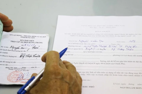 People filling out forms to receive support from the relief package (Photo: VNA)