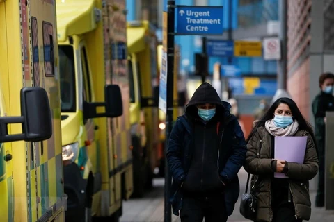 People wearing face masks walk in London, the United Kingdom, on January 26, 2021. (Photo: Xinhua/VNA)