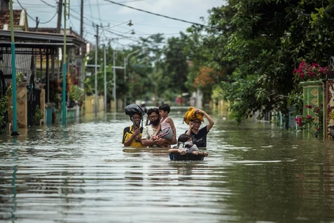Residents evacuate their flooded homes in Gresik, East Java, Indonesia on December 15, 2020, as the rainy season brings floods to many areas in Jakarta and Java. (Photo: AFP/VNA)
