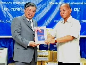 VNA General Director Tran Mai Huong presents book to KPL General Director Khamsen Phongsa (Source:VNA)