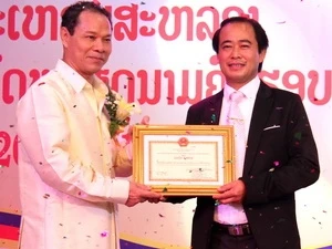 Vietnamese ambassador to Laos Ta Minh Chau presents certificate of merits for Nguyen Duc Moc, Chairman of Vietnam Entrepreneurs’ Association in Laos. Photo: VNA
