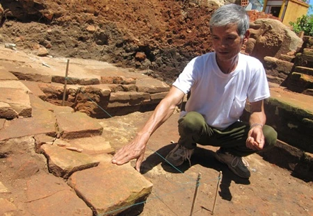 Archaeologist Nguyen Chieu examines a stone which he identified as the step to an entrance of a Cham tower in Qua Giang village in Da Nang city (Photo: VNA)