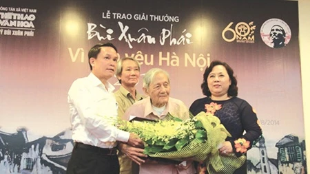 Hanoi researcher Vu Tuan San (centre) receives a bouquet of flowers from Nguyen Thi Bich Ngoc (right), vice chairwoman of Hanoi People's Committee, and Nguyen Duc Loi, general director of the Vietnam News Agency (Photo: VNA)