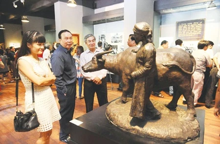 Where the buffalo roam: Visitors examine a depiction of a farmer and his buffalo. The exhibition, featuring 150 photos, artifacts and artworks, brings to life the pivotal nature of the period. — VNA/VNS Photo Minh Duc