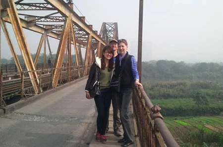 Phung Ngoc Phuong Linh (left) poses with tourists at Ha Noi's historic Long Bien Bridge. (Photo: VNA)