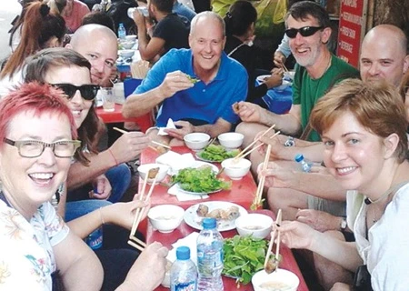 Tourists enjoy nem (deep fried spring rolls) at a street food stall in the Old Quarter. (Photo courtesy of Hanoi Street Food Tour)
