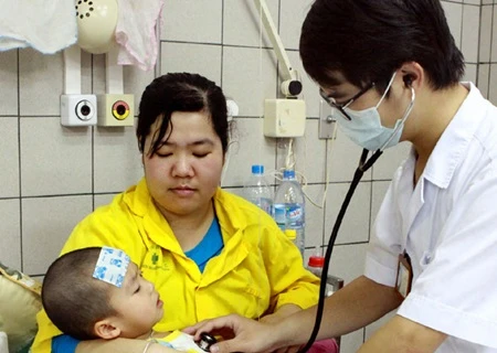 A doctor examines a child at the Paediatrics Ward of Bach Mai General Hospital in Hanoi (Photo: VNA)