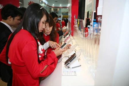 Customers check out applications on smart phones at a Docomo store in Hanoi (Photo: VNA)