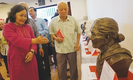 Artist Lai Thi Kim Thanh (left) describes her sculpture of Ho Thi Bi, who was awarded the title of Hero of the People's Armed Forces (Photo: VNA)