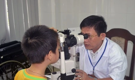 A doctor gives eye check-up to a boy (Photo: VNA)