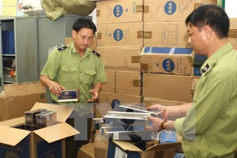 Market watch staff member check seized smuggled tobacco (Photo: VNA)
