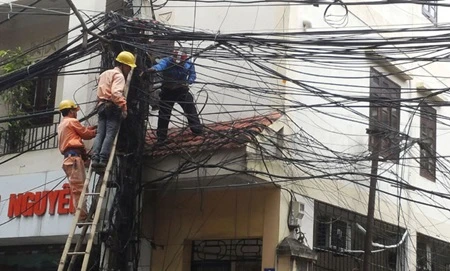 Vietnam Electricity (EVN) workers checkpower lines at a street corner (Photo: VNA)