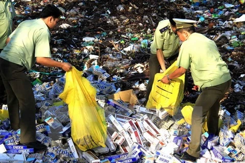Market watch staff members destroy smuggled tobacco (Photo: VNA)