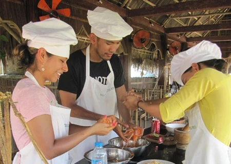Tourists learn how to make salad during a cooking class at Water Wheel Restaurant in Tra Que herb village in Hoi An town (Source: VNA)