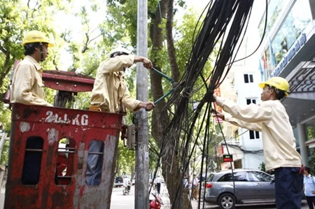 Workers dismantle telecommunications cables in Quang Trung Street in Hanoi (Photo: hanoimoi.com.vn)