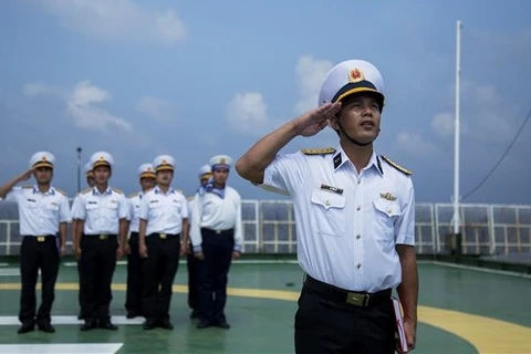 Soldados vietnamitas en plataforma DK1 saludan a la bandera nacional