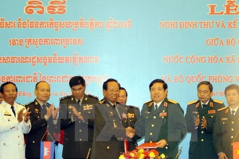 Le ministre vietnamien de la Défense Phung Quang Thanh (droite) et le vice-Premier ministre et ministre de la Défense Tea Banh (gauche) signent un protocole et un plan de coopération entre les deux ministères pour 2015. Photo: VNA