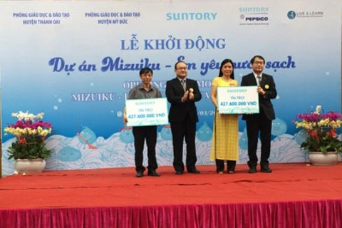 Le président de la compagnie Suntory PepsiCo Vietnam remet l'aide financière au représent du Service de l'éducation et de la formation dans le district de Thanh Oai. 