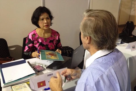 Une représentante de la Chambre d'Industrie et de Commcerce du Vietnam rencontre un client lors de la Fiar-2015. Photo: Dieu Huong/VNA