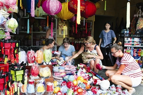 Touristes étrangers achetant des lanternes à Hôi An. Photo : VNP