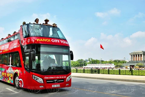 Иностранные туристы наслаждаются пейзажем Мавзолея Хо Ши Мина и площади Бадинь на двухэтажном автобусе. (Фото: ВИА)