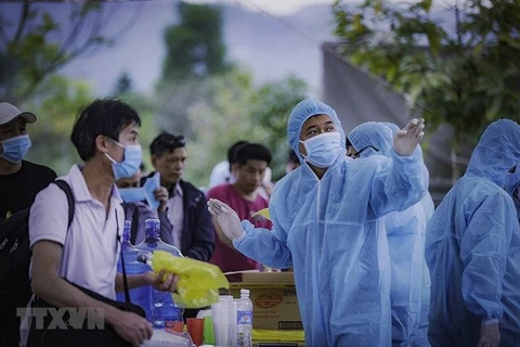 Медицинский работник показывает людям, направляющимся в карантин, путь к их карантинной зоне в провинции Хоабинь (Фото: ВИА)