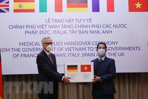 Заместитель министра иностранных дел То Ань Зунг (справа) передает помощь послу Германии во Вьетнаме Гидо Хильднеру (Фото: ВИА)