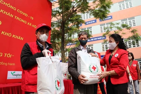 Председатель Центрального комитета общества Красного Креста Вьетнама Нгуен Тхи Суан Тху (справа) предоставляет бесплатную еду нуждающемуся человеку в приходе Дайким, района Хоангмай в Ханое (Фото: ВИА)