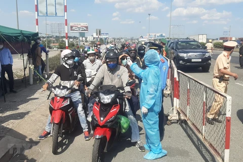 Медицинские работники измеряют температуру тела у въездных дорог города Хошимин. (Фото: Динь Ханг / ВИА)