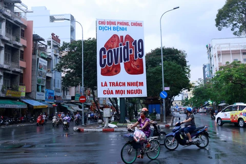 Мотоциклы проезжают мимо рекламного щита, предупреждающего о коронавирусной болезни после ослабления правительством карантинных мер из-за COVID-19 в городе Хошимин во Вьетнаме (Фото: Reuters)
