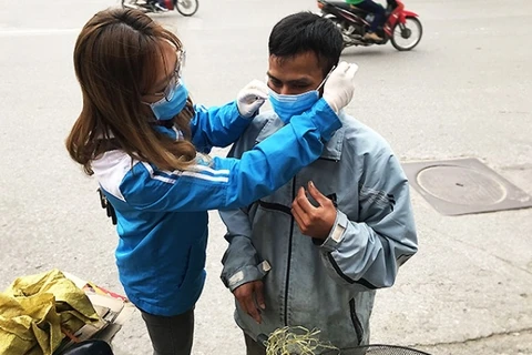 Доброволец одевает маску малоимущему мужчине во время пика эпидемии. (Фото: nhandan.com.vn)
