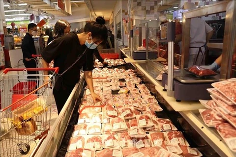 Человек выбирает пачку свинины в супермаркете. (Фото: ВНА)