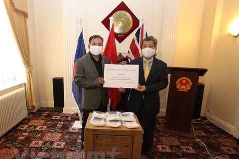 Посол Чан Нгок Ан (Справа) передает антибактериальные маски для лица представителю вьетнамского сообщества в Великобритании. (Фото: ВИА)