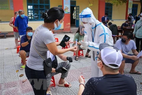 Медицинский персонал раздает иностранцам пробирки для проб в районе Шонча (Дананг). (Фото: ВИА)