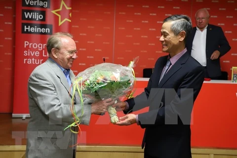 Посол Вьетнама в Германии Нгуен Минь Ву дарит цветы немецкому журналисту Хельмуту Капфенбергеру на церемонии открытия. (Фото: ВИА)