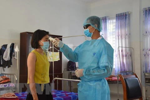 Медсестра измеряет температуру тела у людей, находявшихся в карантинной зоне в провинции Бариа-Вунгтау. (Фото: ВИА)