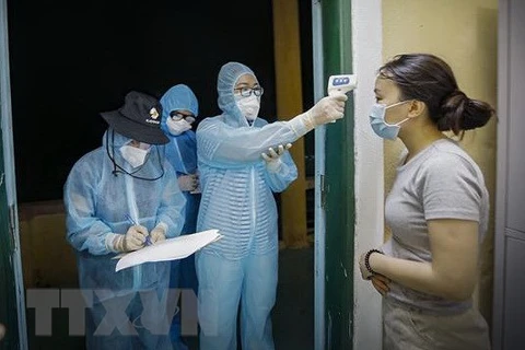 Медсестра измеряет температуру тела у людей, находявшихся в карантинной зоне в провинции Хоабинь. (Фото: ВИА)