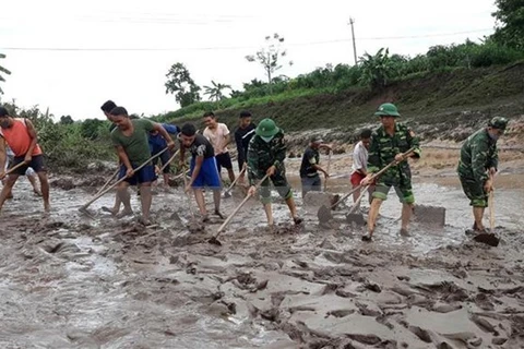 Пограничники и местные жители в районе Хыонгхоа в Куангчи убирают грязь, оставшуюся после наводнения на дорогах (Фото: ВИА)