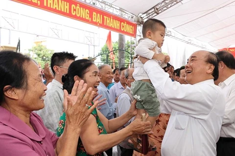 Премьер-министр Нгуен Суан Фук держит на руках ребенка во время празднования Дня великого национального единства в провинции Хайзыонг 18 ноября (Фото: ВИА) 