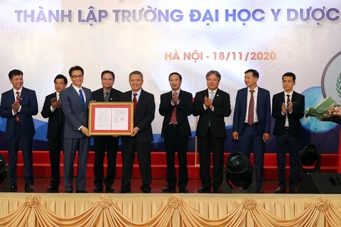 Заместитель премьер-министра Ву Дык Дам (слева) представляет на мероприятии решение премьер-министра о создании Университета медицины и фармации (Фото: ВИА)